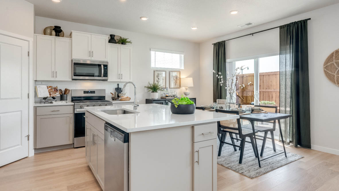 Davis Estates Kitchen with solid quartz countertops, in-island sink with a breakfast bar, stainless steel appliances, shaker style cabinets, pantry, decorative hanging decoration, dining room table, sliding glass door with shades