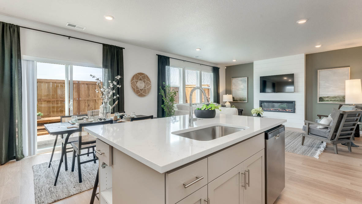 Davis Estates Kitchen with solid quartz countertops, in-island sink with a breakfast bar, stainless steel appliances, and great room in the background