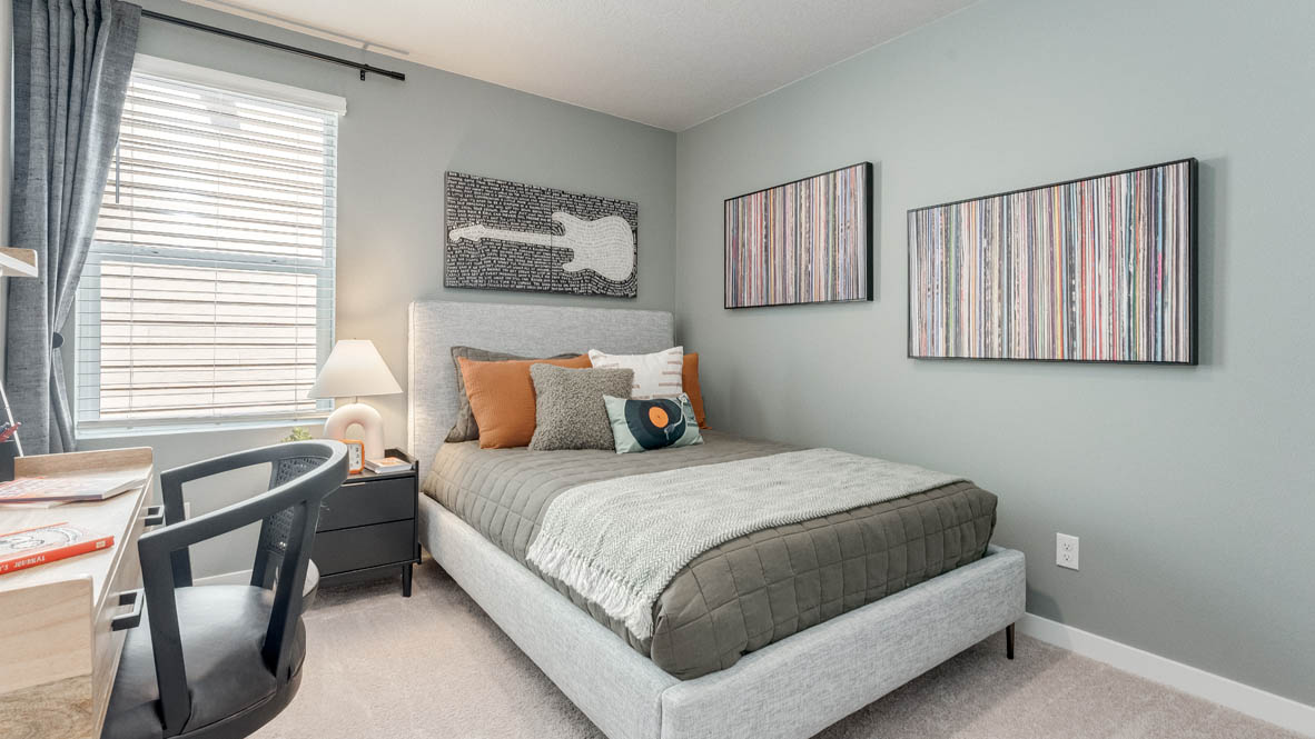 Davis Estates bedroom with side table and a lamp, bed, paintings, desk with a chair, and window with shades