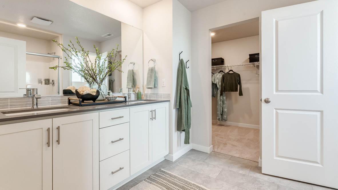 Davis Estates primary bathroom with flooring, shaker cabinets, double vanity, quartz countertops, walk-in closet, paintings, mirror