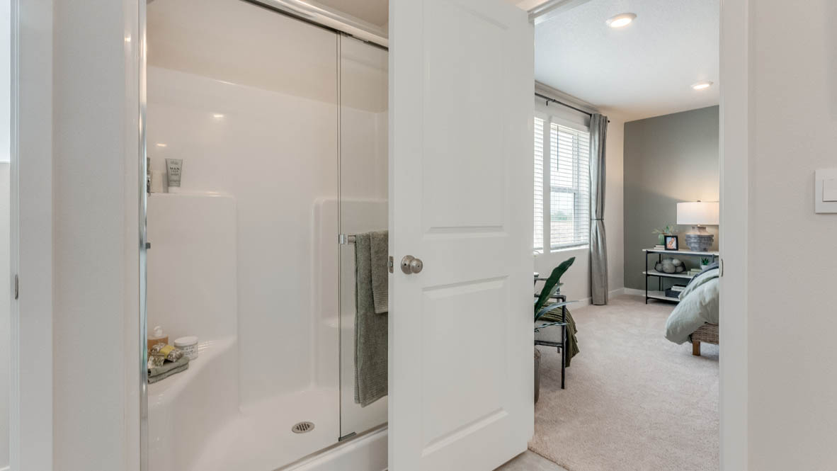 Davis Estates primary bathroom with a walk-in shower with sliding glass doors, and primary bedroom in the background