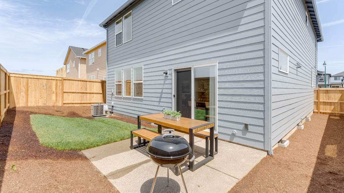 Davis Estates backyard with a table, bark dust, a fence, and grass