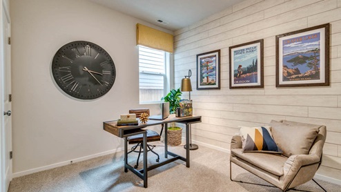 Marcola Meadows den with carpeting, shiplap accent wall, desk set up with a leather chair, three art prints, and a bookshelf