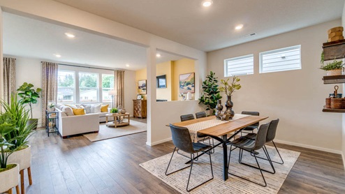 Marcola Meadows main dining room with a six chair dining set placed over an area rug, a half wall with an opening, two windows, and floating shelves