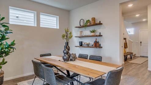 Marcola Meadows main dining room with a six chair dining set placed over an area rug, a half wall with an opening, two windows, and floating shelves