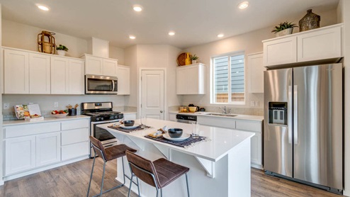 Marcola Meadows kitchen with white shaker style cabinets, stainless steel appliances, white quartz countertops, a kitchen island with two high seated stools, a pantry, and kitchen decor