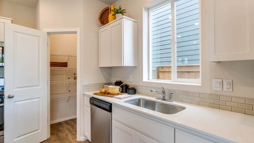 Marcola Meadows kitchen with white shaker style cabinets, stainless steel appliances, white quartz countertops, a kitchen island with two high seated stools, a pantry, and kitchen decor