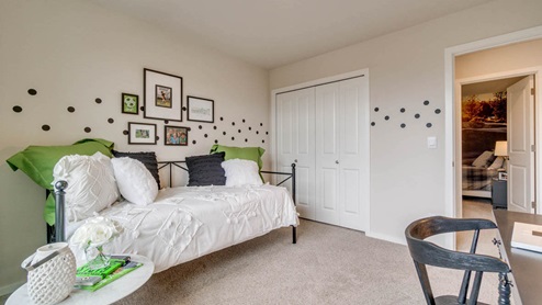 Marcola Meadows bedroom with a black metal rod day bed, white bedding with green and black accent pillows, green curtains, and a black desk
