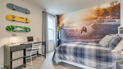 Marcola Meadows bedroom with skateboard themed wall paper and wall art, blue plaid bedding, and a gray desk with a white desk chair over carpeting