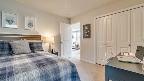 Marcola Meadows bedroom with skateboard themed wall paper and wall art, blue plaid bedding, and a gray desk with a white desk chair over carpeting
