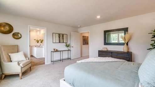 Marcola Meadows Primary Bedroom with carpeted flooring, grayish green accent wall, white fabric bedframe with light sage bedding, and brown wood accent furniture