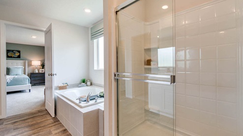 Marcola Meadows primary bathroom with two sink vanity, toilet closet, walk in shower with glass doors, laminate flooring and a carpeted walk in closet