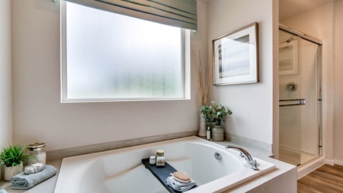 Marcola Meadows primary bathroom with two sink vanity, toilet closet, walk in shower with glass doors, laminate flooring and a carpeted walk in closet