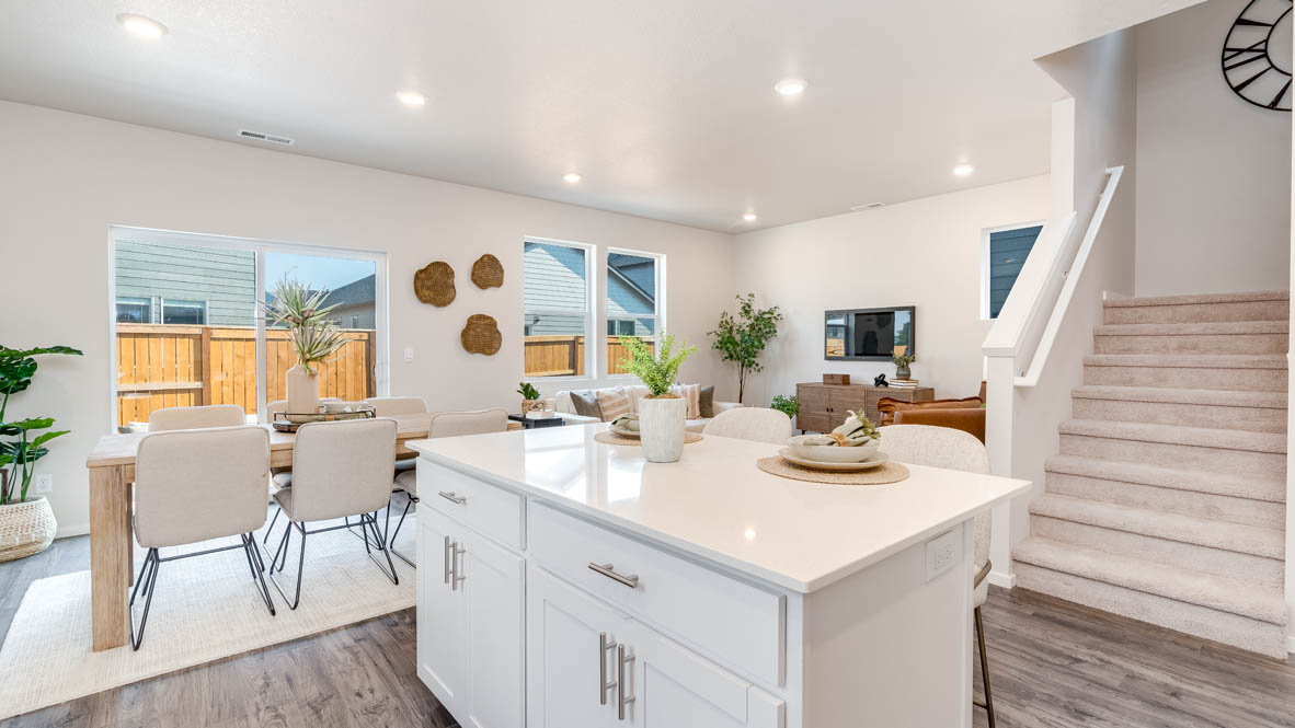 Marcola Meadows kitchen with an island, quartz countertops, white cabinets, flooring, and the staircase, and dining room in the background