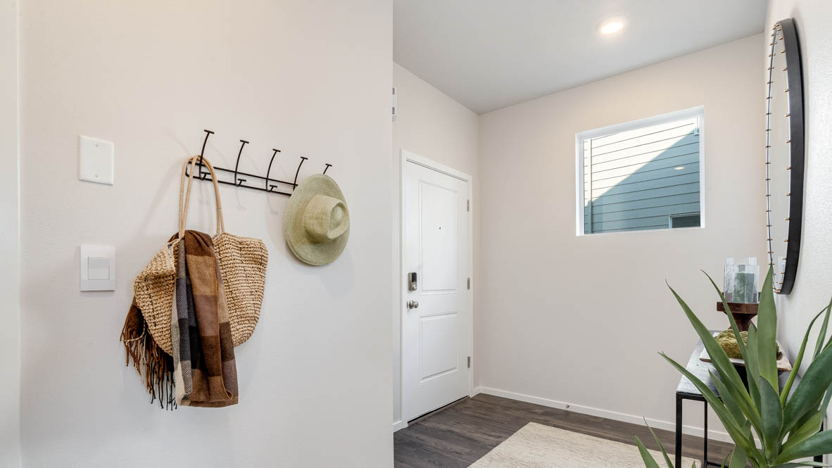 Marcola Meadows Entry with a coat rack, a runner rug, plants, a window, white walls, and front entry door