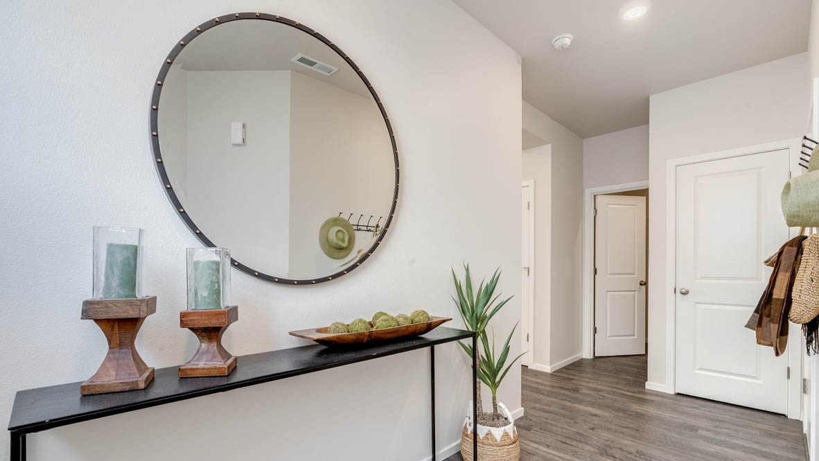 Marcola Meadows Entry with a entry table, circle mirror, plants, flooring, white walls, and a coat rack