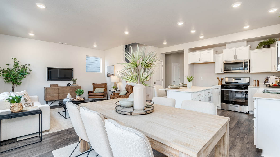 Marcola Meadows Dining room with rug, table with four chairs, two decorative paintings, three hanging decorations, and the kitchen and great room in the background