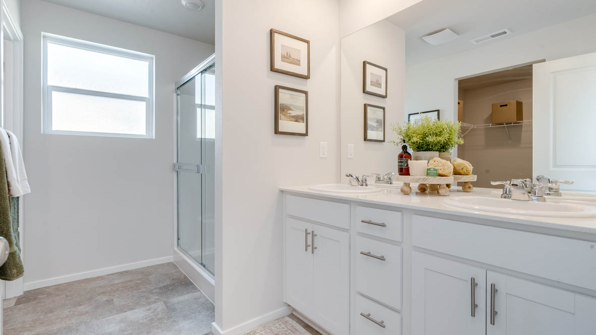 Marcola Meadows Primary bathroom with quartz countertops, mirror, paintings, window, and walk in shower