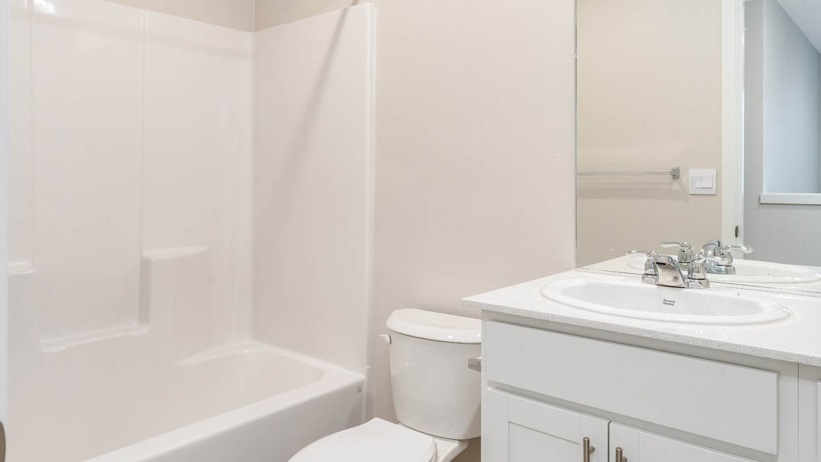 Marcola Meadows hall bathroom with white tub, walls, sink, cabinets, and toilet