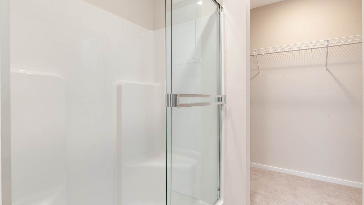 Marcola Meadows primary bathroom walk-in shower with sliding glass door and view of walk-in closet