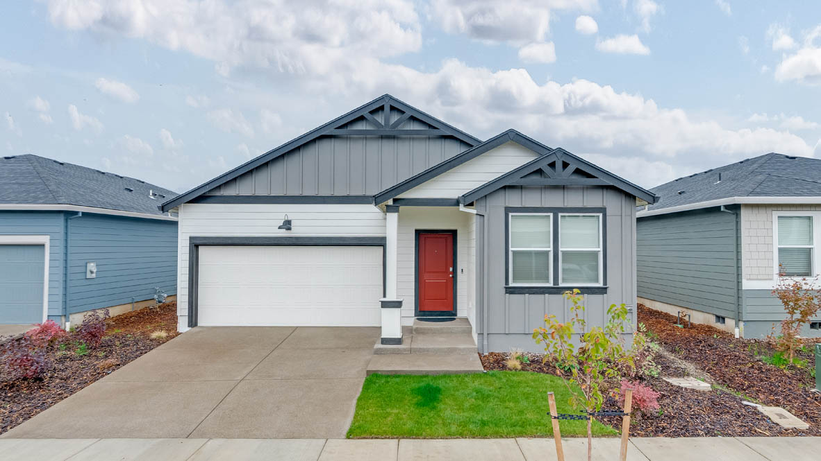 Marcola Meadows Single-story home with gray siding and a covered porch and two-car garage.