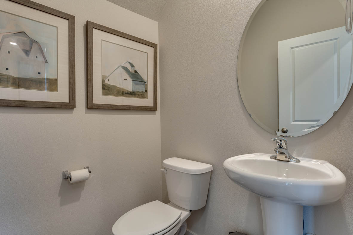 Marcola Meadows Powder room with a white toilet, single sink and circle mirror
