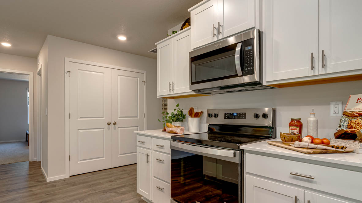Eden Estates kitchen with laminate flooring, stainless steel appliances, cabinets, window, solid surface countertops