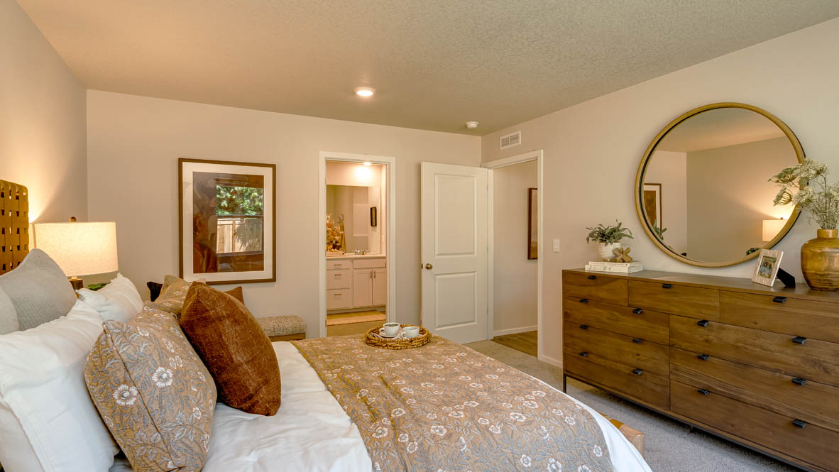 Eden Estates primary bedroom with 2 nightstands, a bed with white sheets and accent blanket,  closet