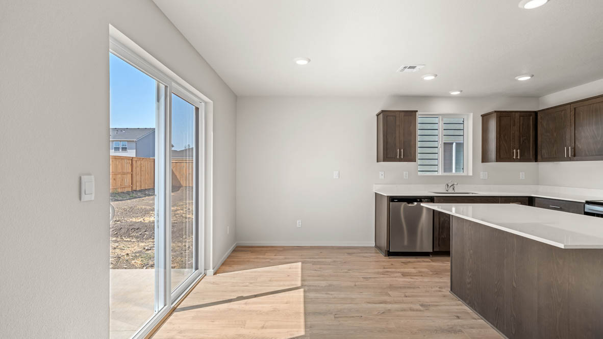Eden Estates dining room with laminate flooring, windows, and the kitchen in the background