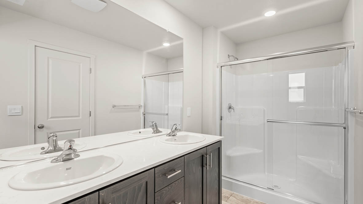 Eden estates primary bathroom with solid surface countertops, mirror, walk in shower, and cabinets