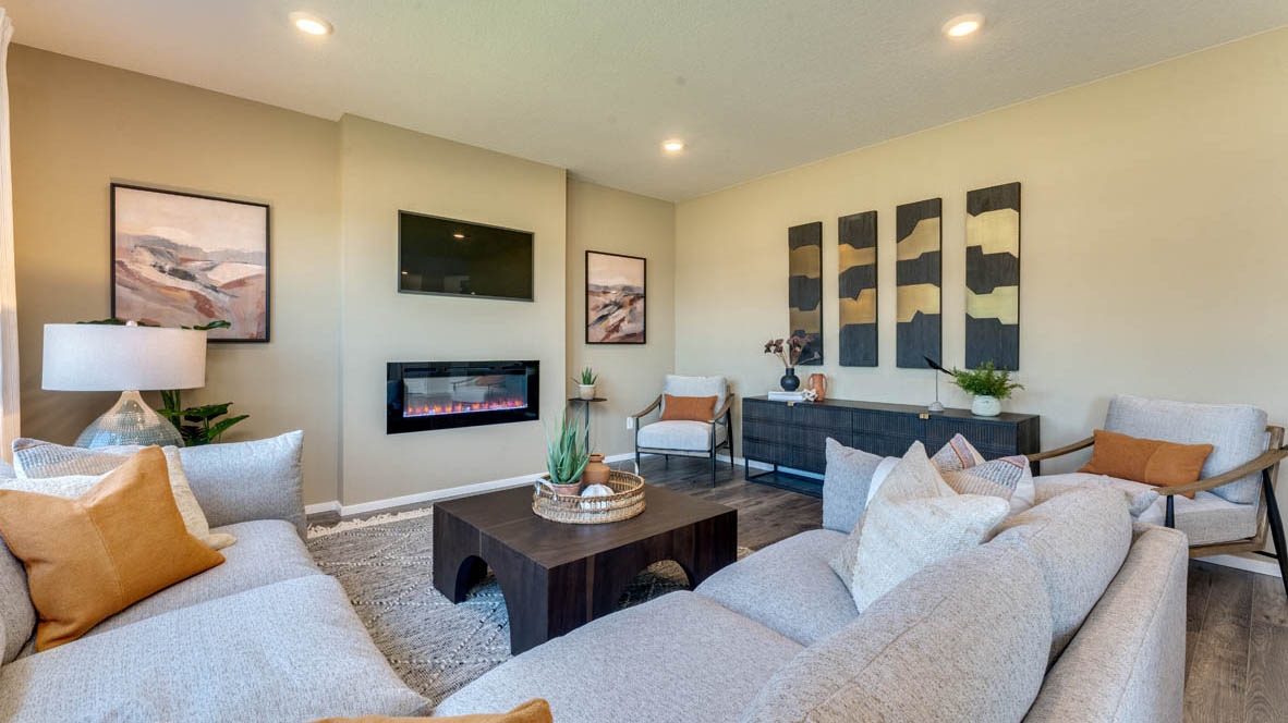 Eden Estates great room with white couch, chair, coffee table, paintings, lamp, rug, windows with curtains