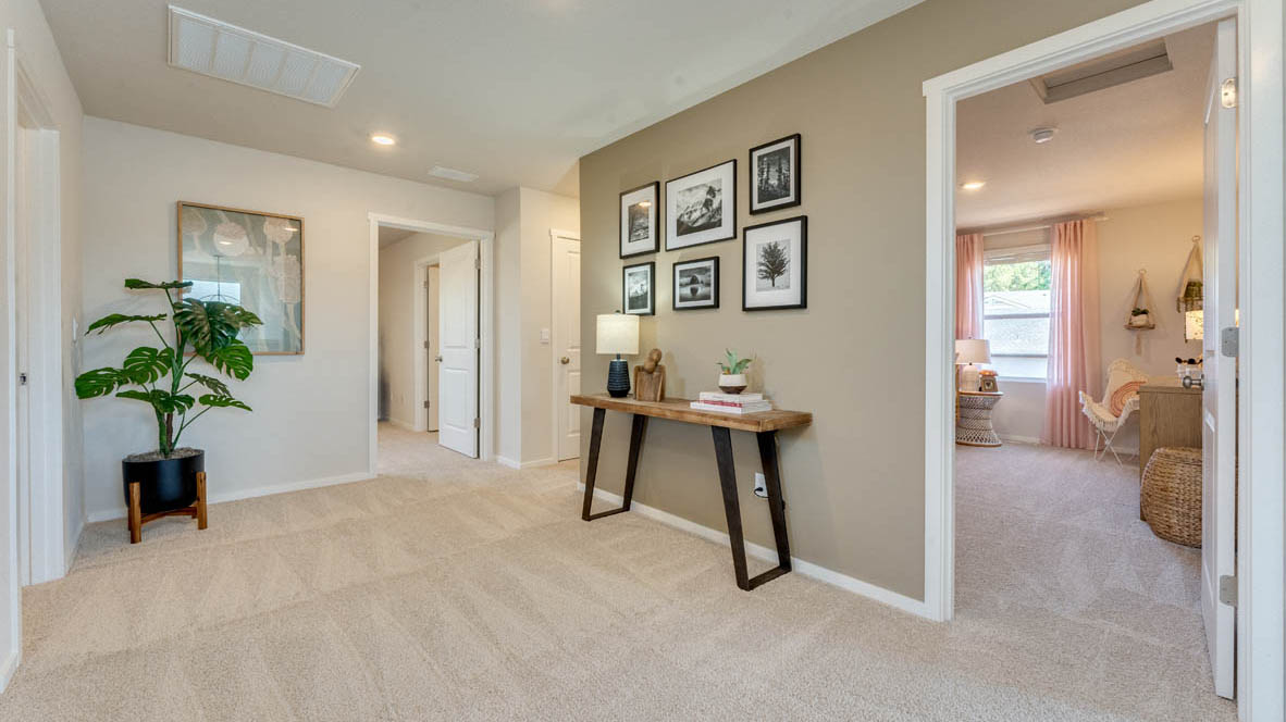 Eden Estates bedroom with side table and a lamp, bed, paintings, desk with a chair, and window with shades