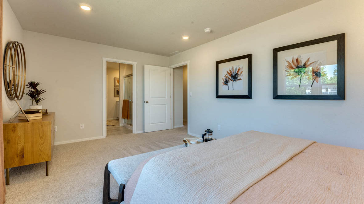 Eden Estates Primary bedroom with white carpet, painting, and the en suite bathroom in the background
