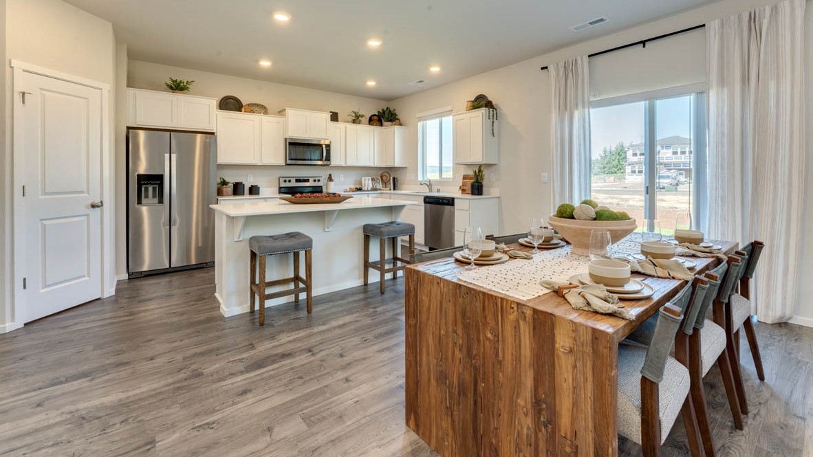 Eden Estates Kitchen with solid quartz countertops, in-island sink with a breakfast bar, stainless steel appliances, shaker style cabinets, pantry, decorative hanging decoration, dining room table, sliding glass door with shades