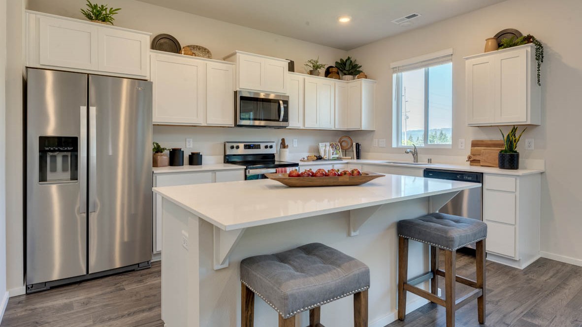 Eden Estates Kitchen with solid quartz countertops, in-island sink with a breakfast bar, stainless steel appliances, shaker style cabinets, pantry, decorative hanging decoration, dining room table, sliding glass door with shades