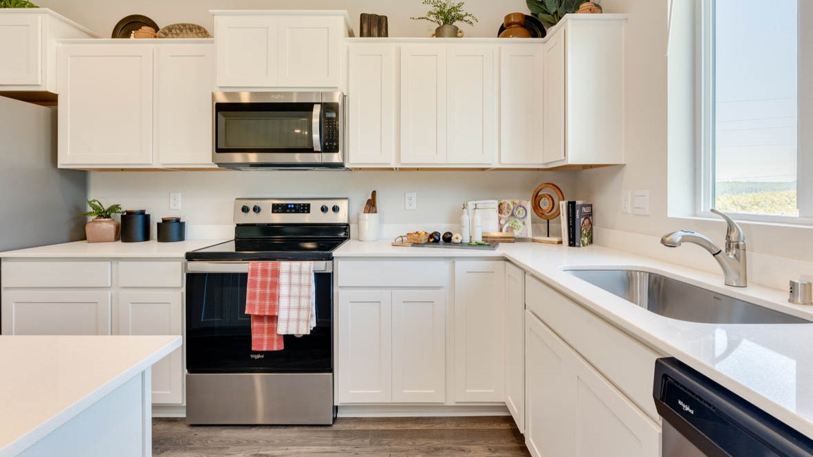 Eden Estates Kitchen with solid quartz countertops, in-island sink with a breakfast bar, stainless steel appliances, shaker style cabinets, pantry, decorative hanging decoration, dining room table, sliding glass door with shades