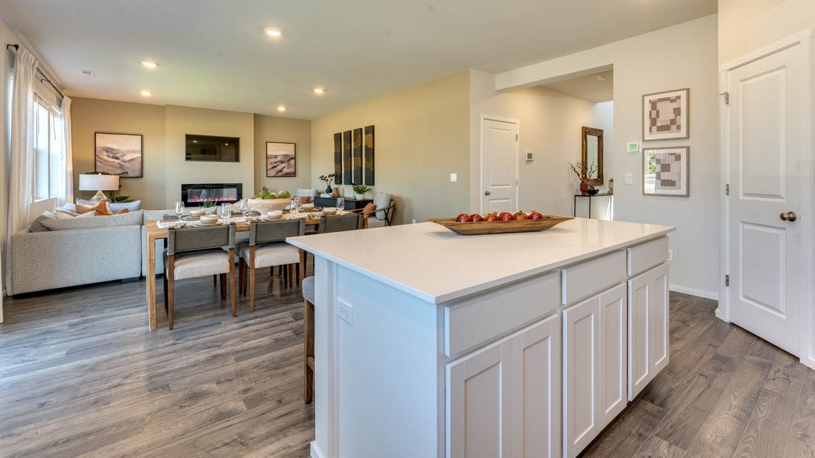 Eden Estates Kitchen with solid quartz countertops, in-island sink with a breakfast bar, stainless steel appliances, shaker style cabinets, pantry, decorative hanging decoration, dining room table, sliding glass door with shades