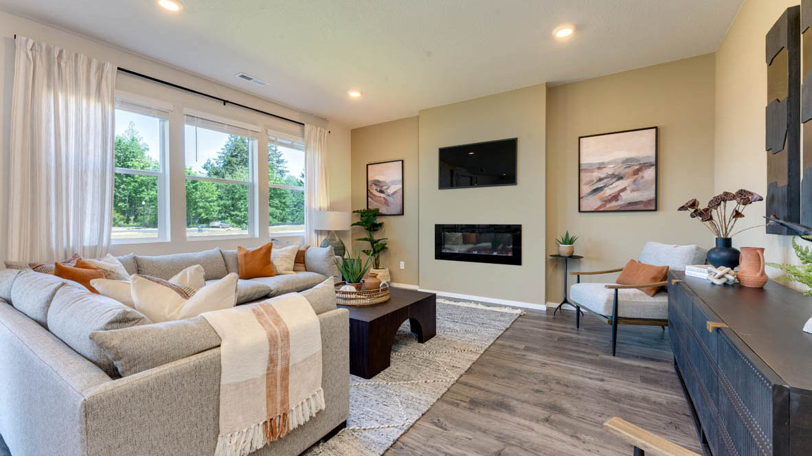 Eden Estates great room with white couch, chair, coffee table, paintings, lamp, rug, windows with curtains