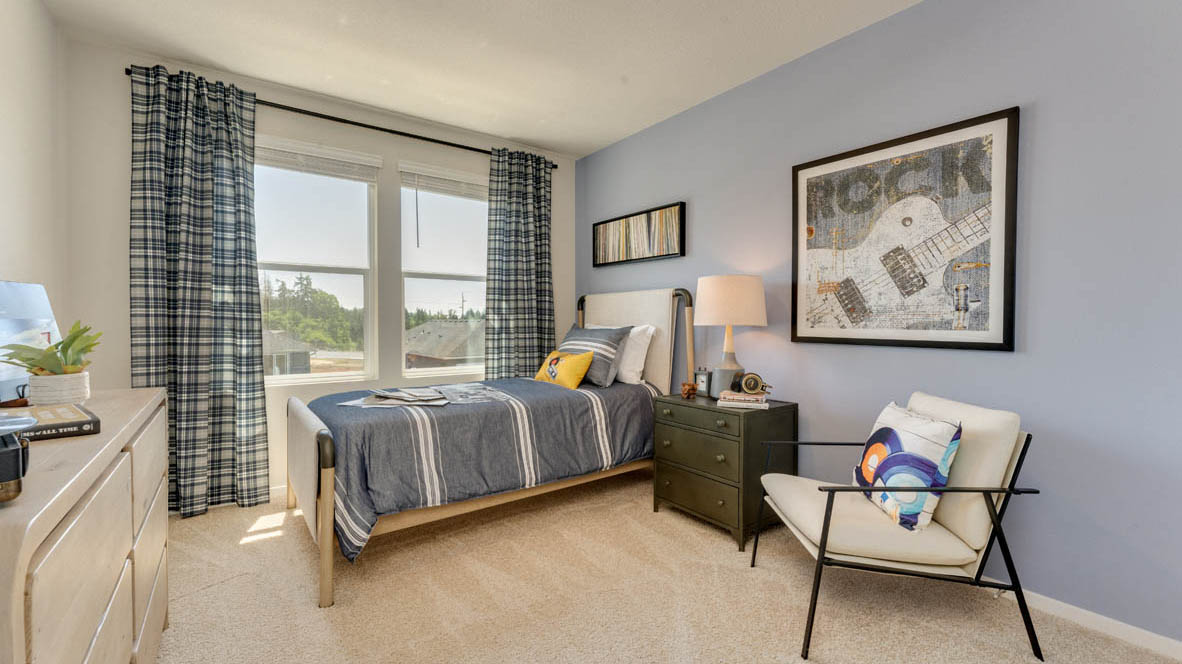 Eden Estates bedroom with side table and a lamp, bed, paintings, desk with a chair, and window with shades