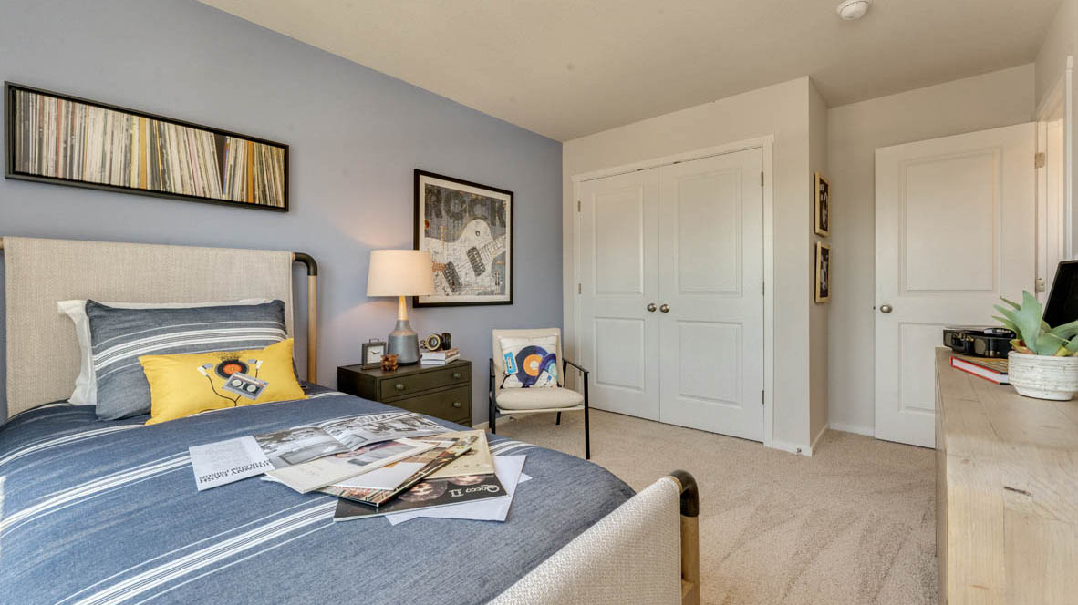 Eden Estates bedroom with bed, closet, nighstand with lamp, blue comforter