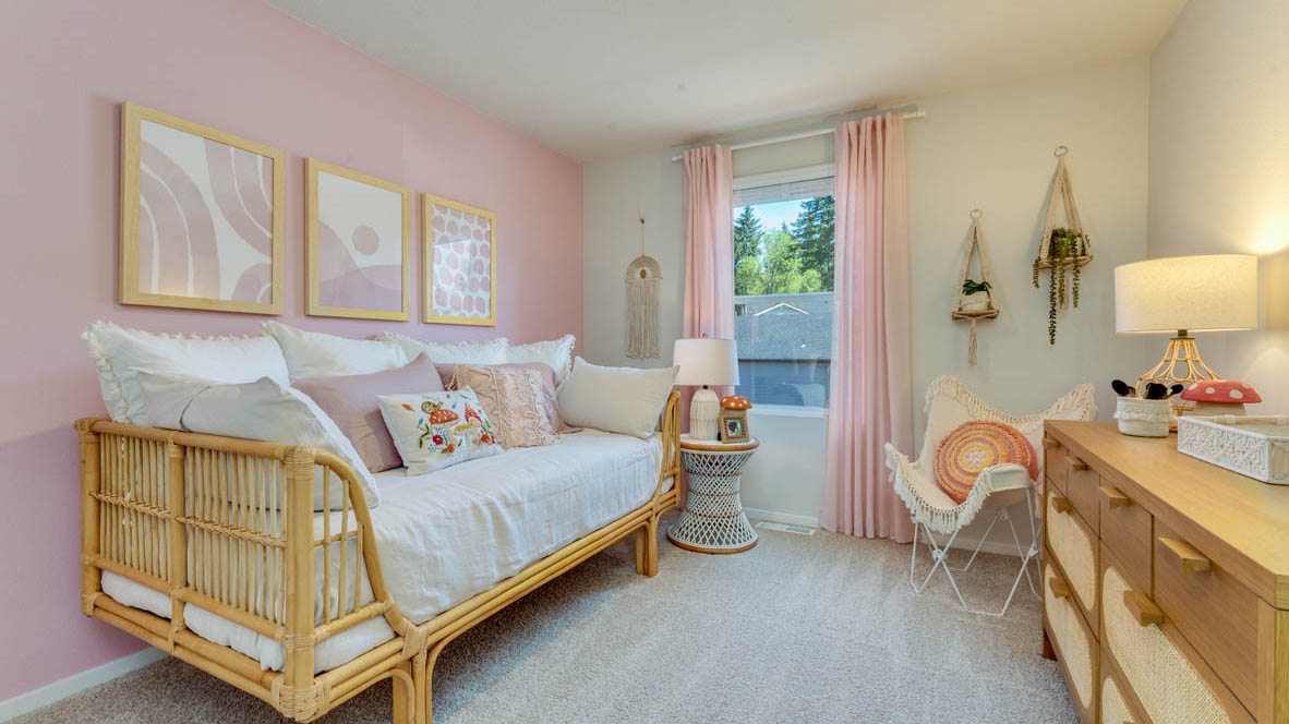 Eden Estates bedroom with couch, pink accent walls, white carpet, nightstand with a lamp