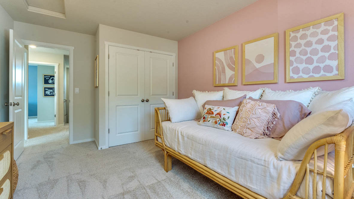 Eden Estates bedroom with couch, pink accent walls, white carpet, nightstand with a lamp, closet