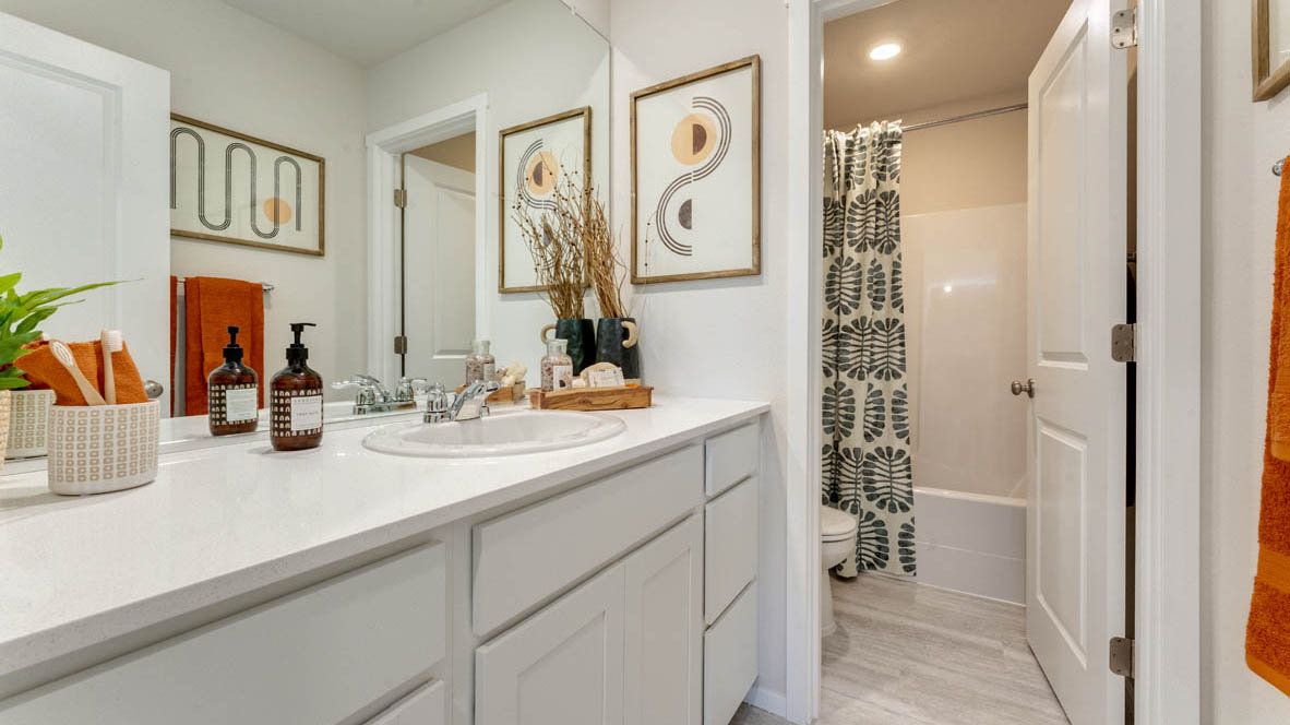 Eden Estates bathroom with solid surface countertops, mirror, and walk in shower
