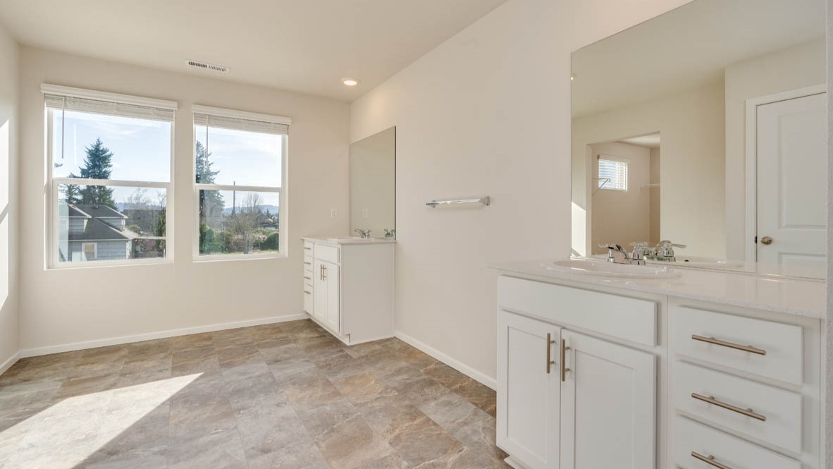 Eden estates primary bathroom with solid surface countertops, mirror, walk in shower, and cabinets