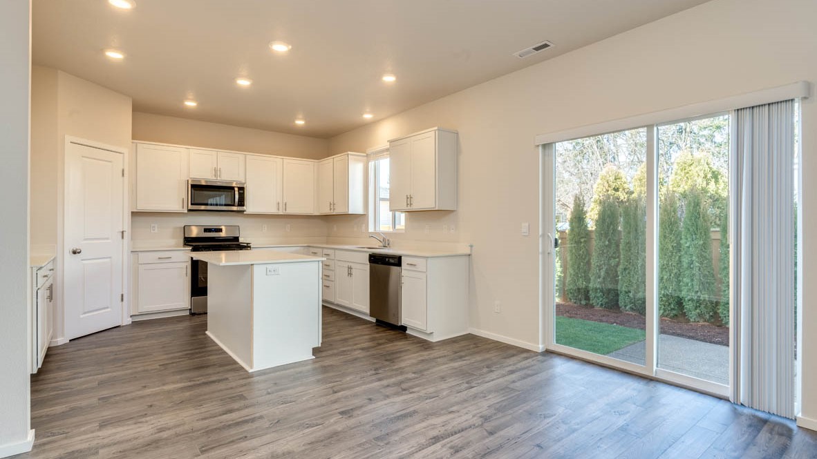 Eden Estates dining room with laminate flooring, windows, and the kitchen in the background