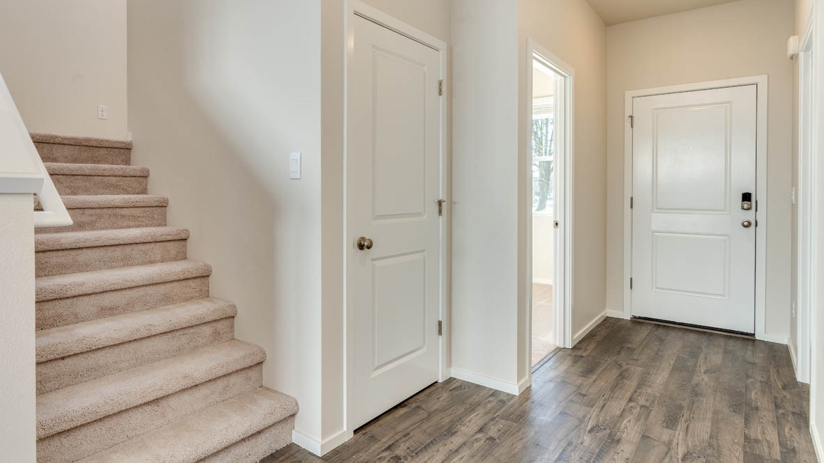 Eden Estates Entry with carpeted stairs, laminate flooring, and white walls