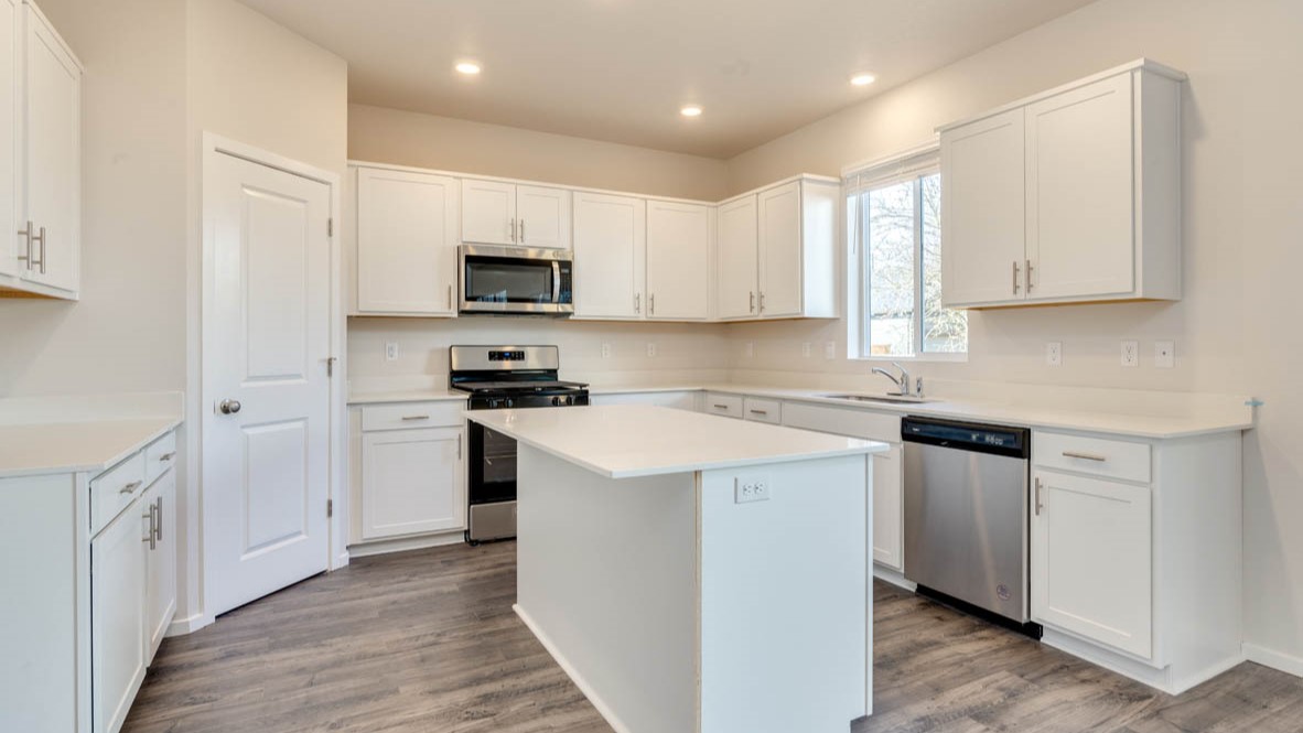 Eden Estates kitchen with laminate flooring, stainless steel appliances, cabinets, window, solid surface countertops