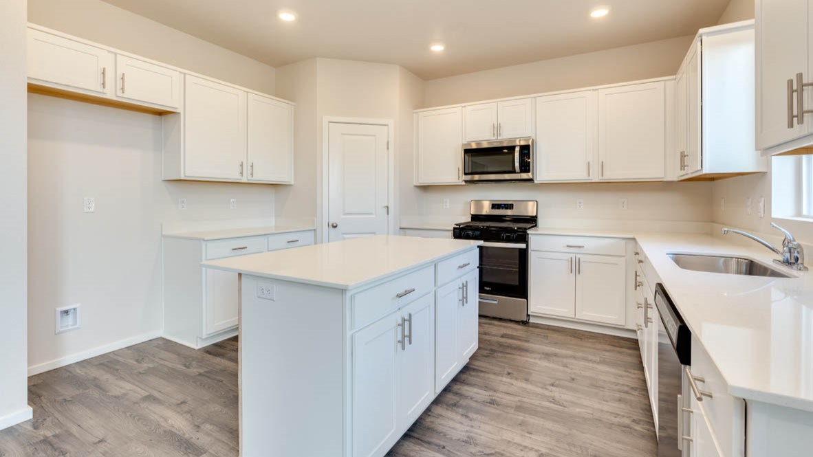 Eden Estates kitchen with laminate flooring, stainless steel appliances, cabinets, window, solid surface countertops