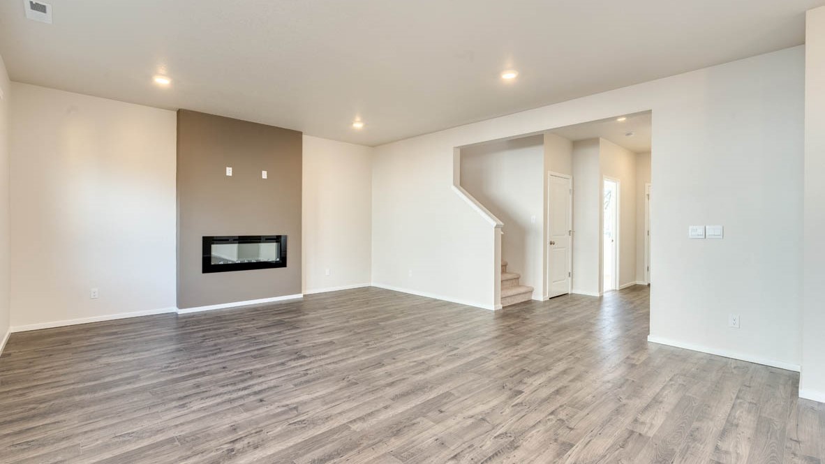 Eden Estates great room with fireplace, laminate flooring, and the stairs in the background