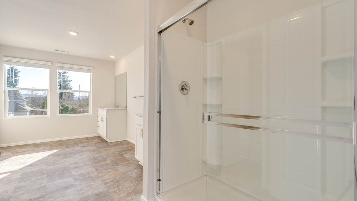 Eden estates primary bathroom with solid surface countertops, mirror, walk in shower, and cabinets